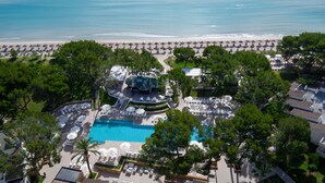 Luchtbeeld van een resort met een zwembad, strandparasols en ligbedden.