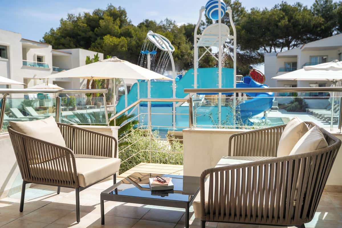 Un espace aménagé au bord de la piscine, avec des meubles en osier, des parasols et une structure ludique aquatique.