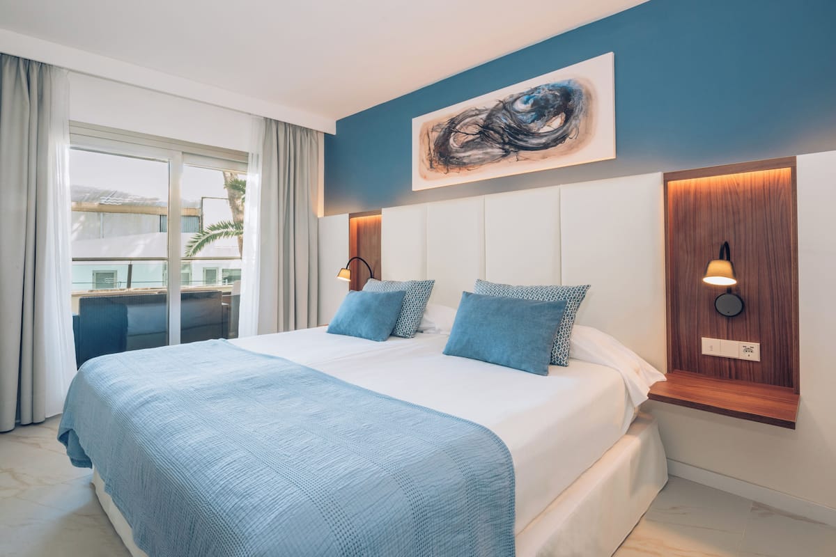 Une chambre d’hôtel moderne avec un grand lit, une vue sur l’extérieur et un tableau au mur.