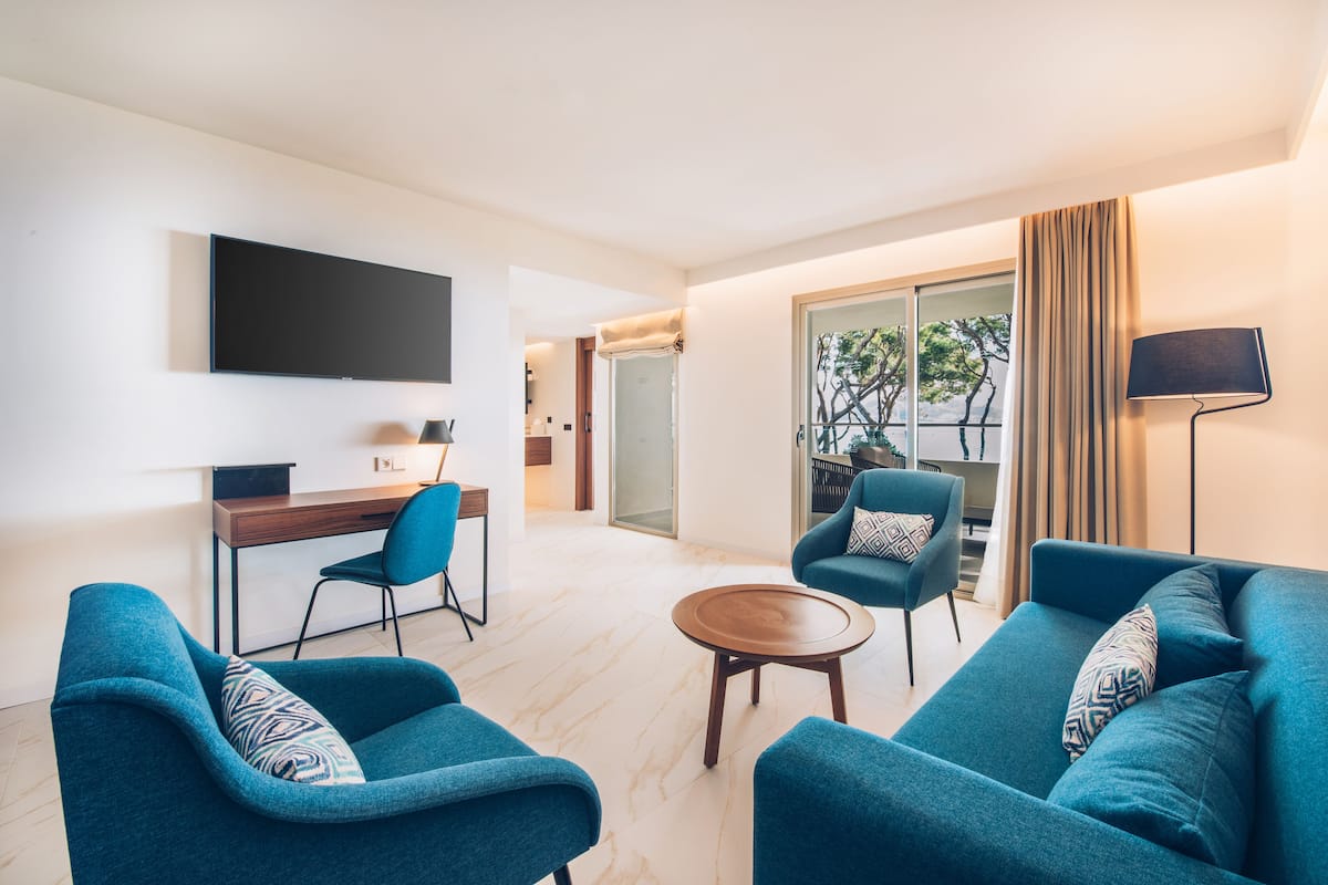 Un salon moderne avec un téléviseur à écran plat, deux canapés bleus, une table basse en bois et un bureau avec une chaise.
