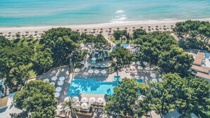 Een vogelvluchtperspectief van een resort met een zwembad, strand en weelderige begroeiing.