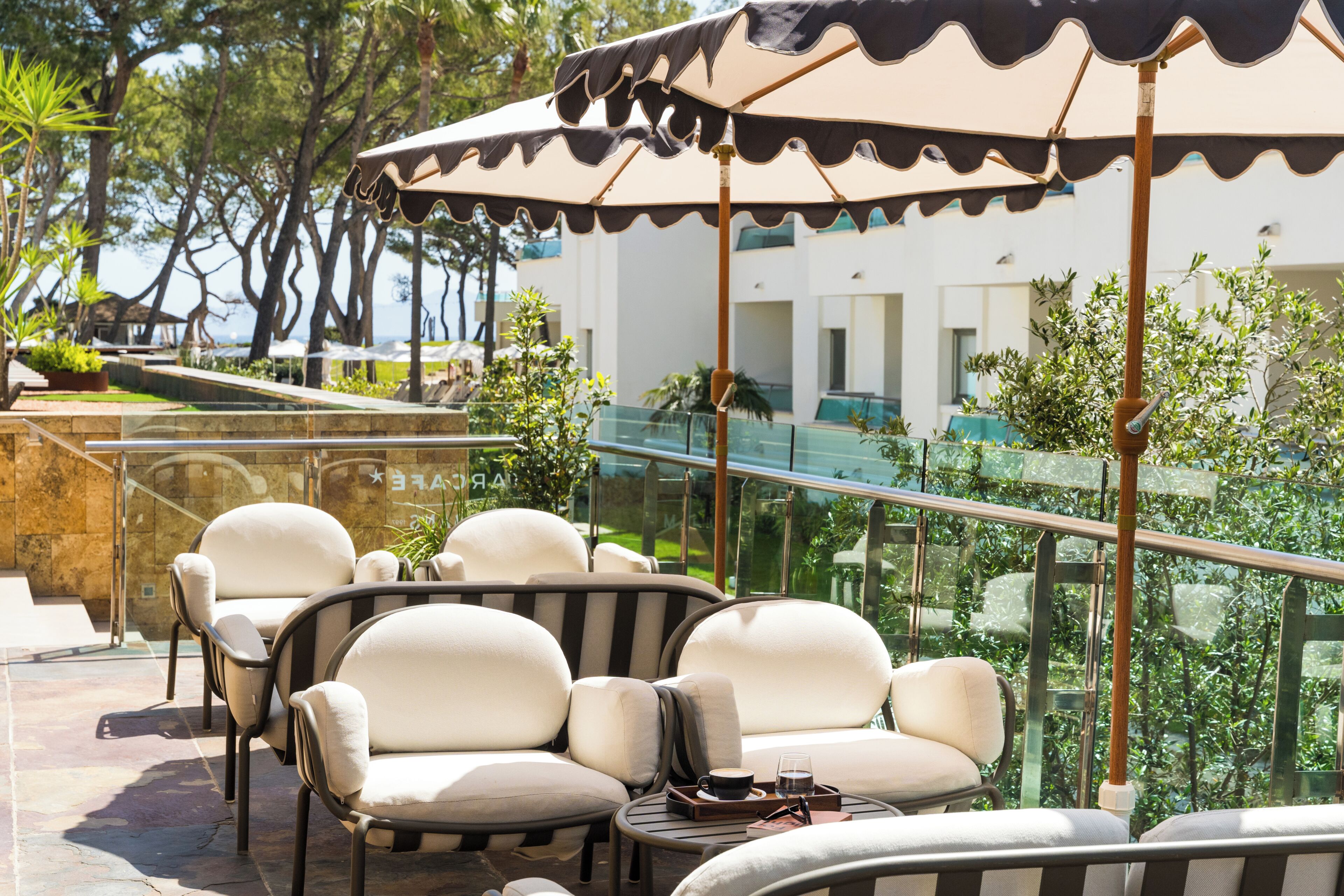 A terrace with outdoor seating, a glass balustrade, and a view of the sea.