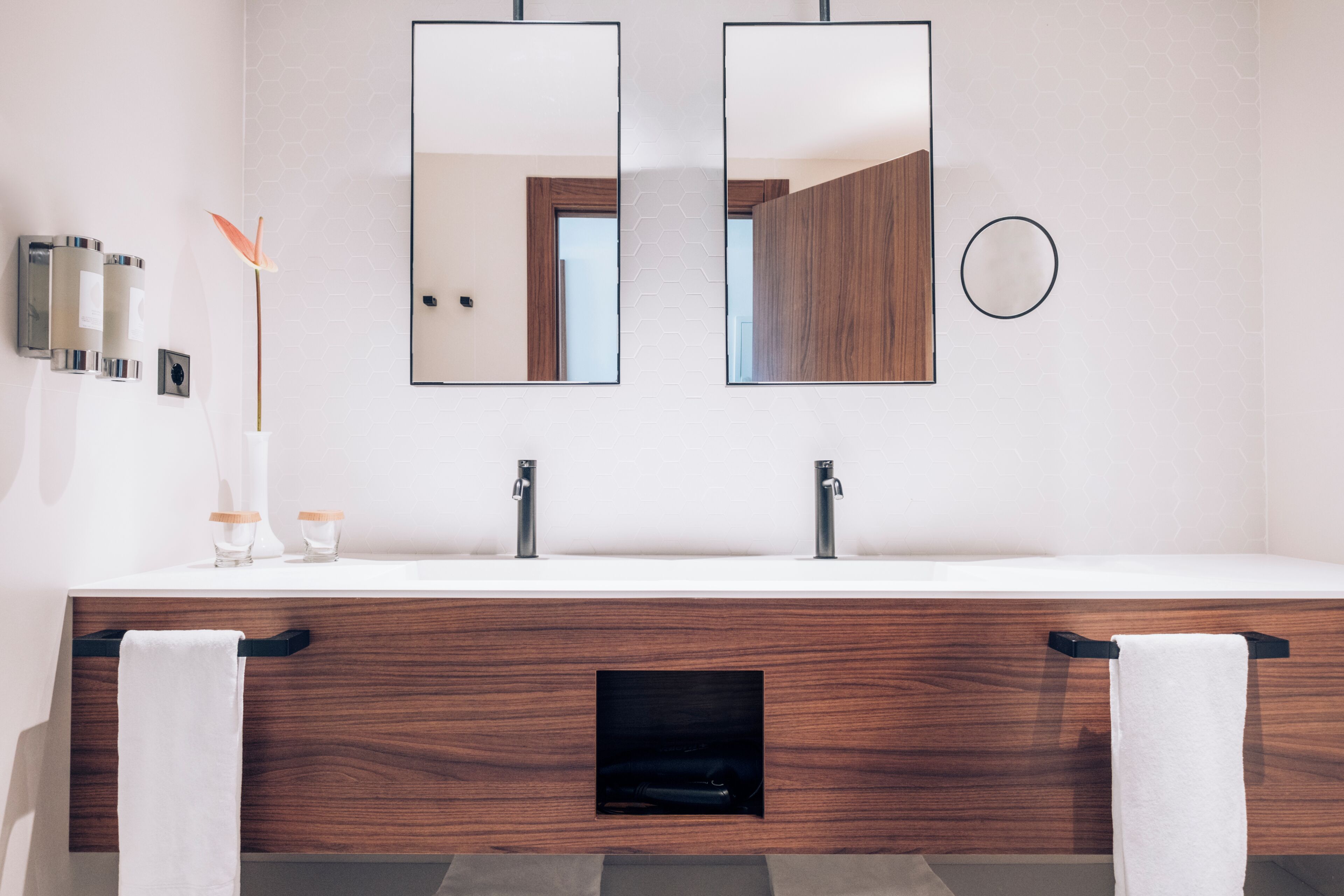 Un bagno con un mobile bagno in legno, due specchi e un portasciugamani.