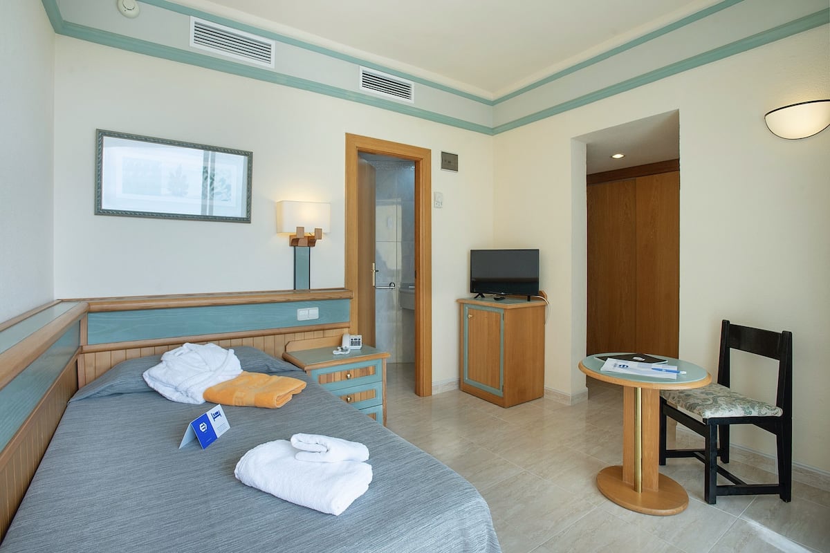 Een hotelkamer met een bed, een bureau, een stoel, een televisie en een tafeltje.