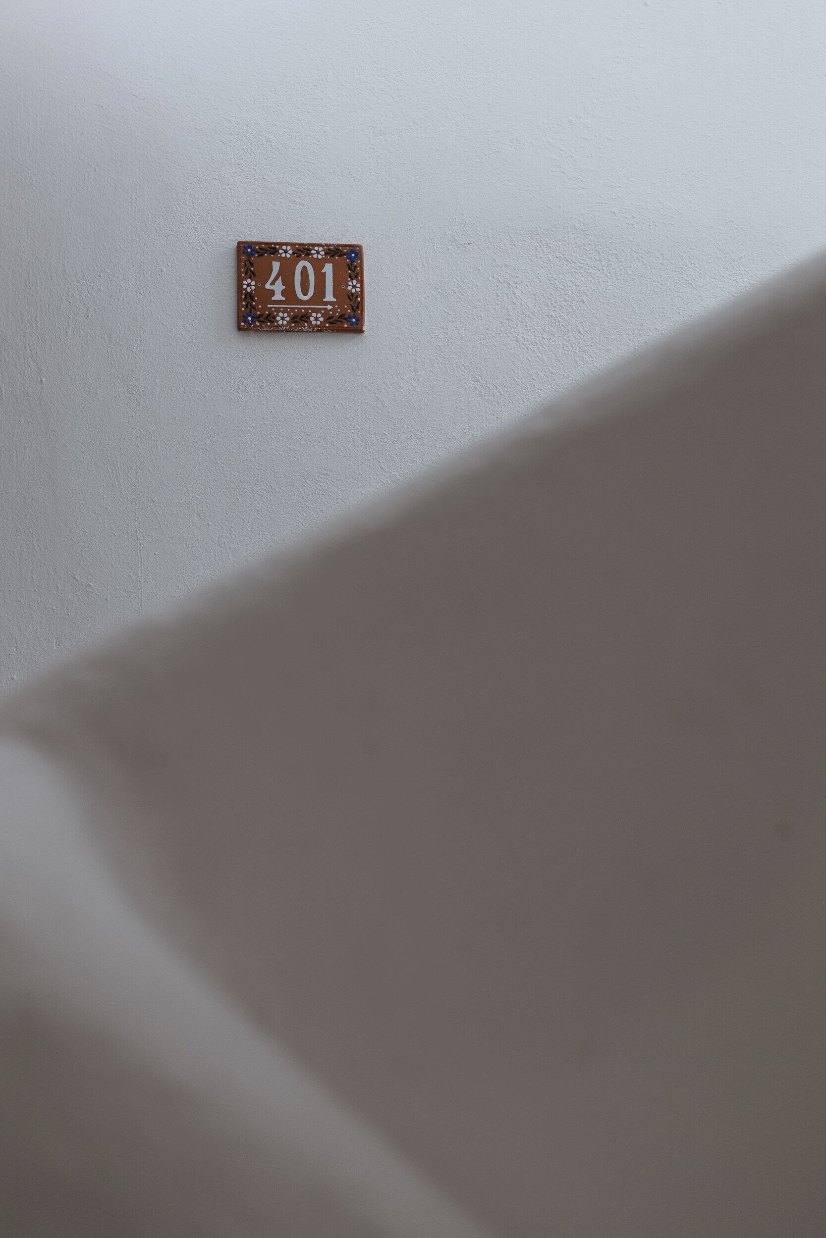 Pequeño letrero decorativo con el número '401' sobre una pared blanca.