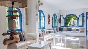 A spacious living area with white sofas, a coffee table, and a hanging light fixture. - Nathalie Hotel (Rhodes)