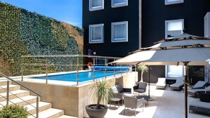 Un espace piscine sur le toit, offrant une vue sur la montagne, avec des sièges extérieurs et un escalier menant à la piscine.