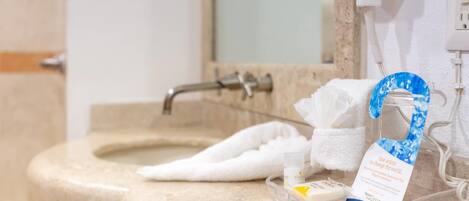 A bathroom sink with a towel, a soap dispenser, and a glass container with a label.