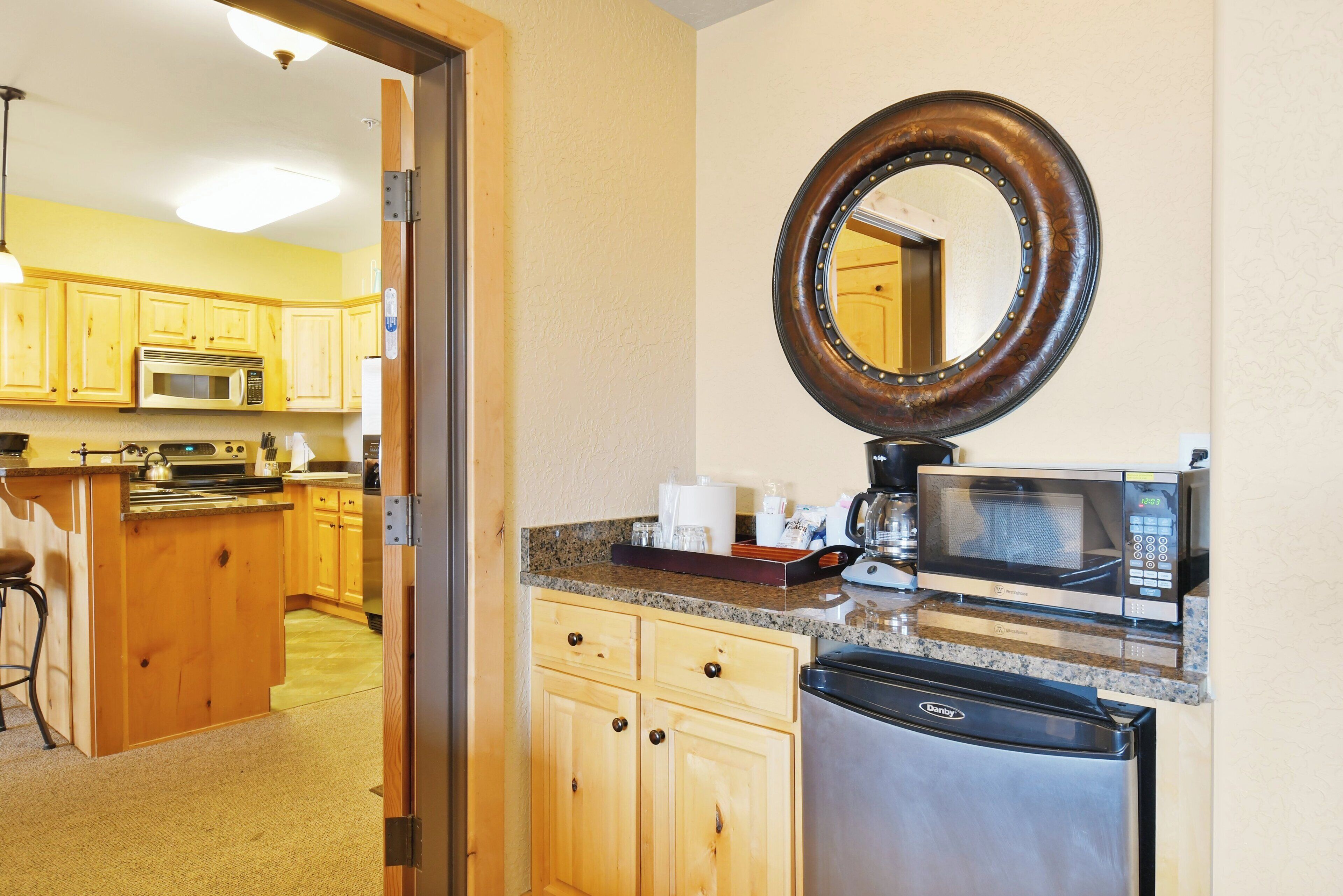 A kitchen with wooden cabinets, a microwave, a dishwasher, and a large mirror.