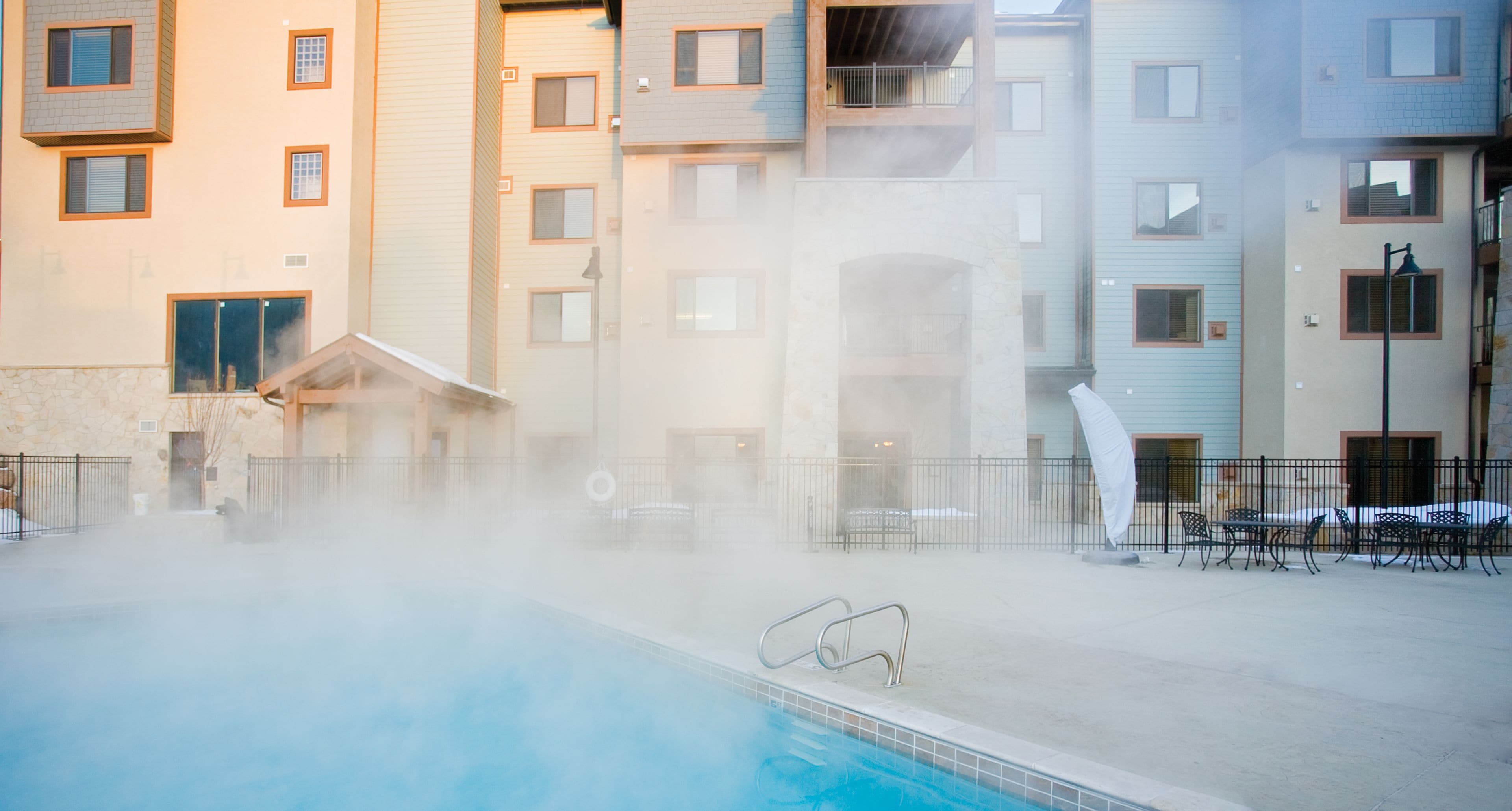 Piscina rodeada por um edifício com várias varandas e janelas.