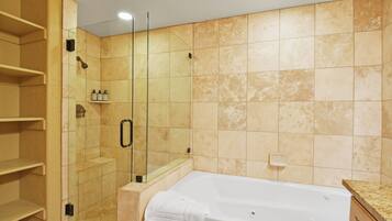 Une salle de bain avec une douche à parois de verre, une baignoire blanche et des murs recouverts de carreaux beiges.