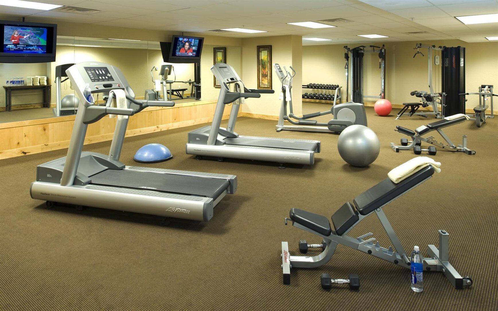 Een sportschool met loopbanden, fitnessballen en gewichtstoestellen.