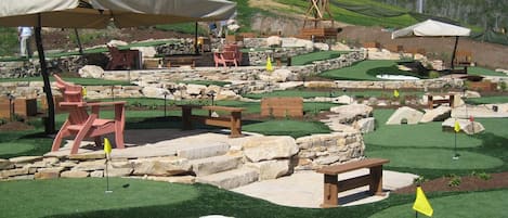 A miniature golf course with artificial grass, sand traps, and stone walls.