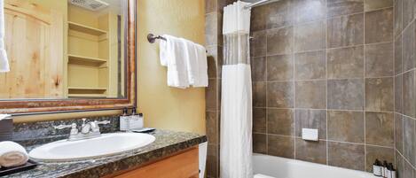A bathroom with a sink, mirror, toilet, and bathtub.