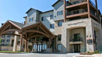 A multi-story building with a stone facade, balconies, and a clear sky.