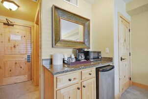 Una cocina compacta con muebles de madera, un microondas integrado y una cafetera.