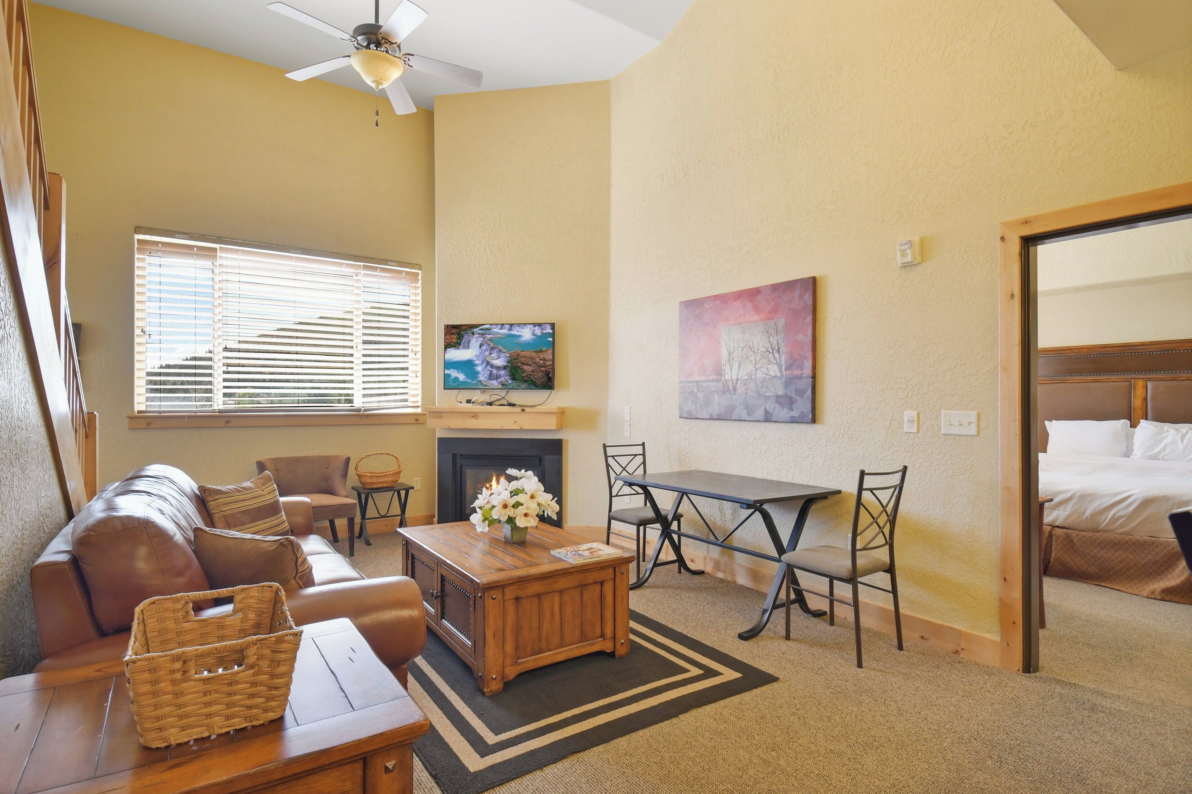 Una sala de estar acogedora con chimenea, televisor y comedor con sillas y una mesa.