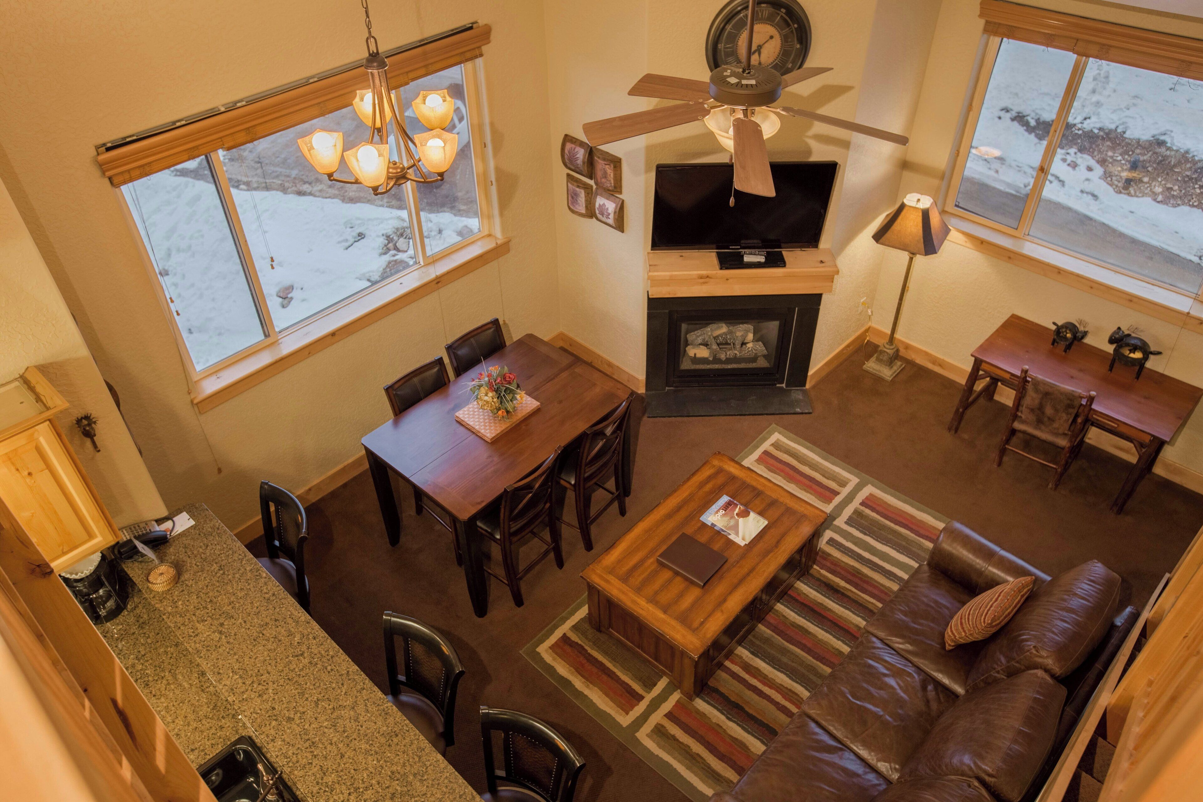 A cozy living room with a fireplace, a dining area, and a kitchen.