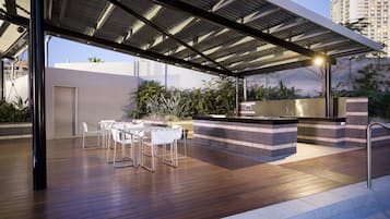 An outdoor patio with a wooden deck, a covered seating area, and a built-in barbecue station.