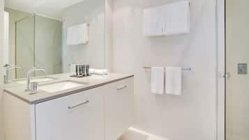 A modern bathroom with a glass shower enclosure, a double sink vanity, and two towels hanging on the wall.
