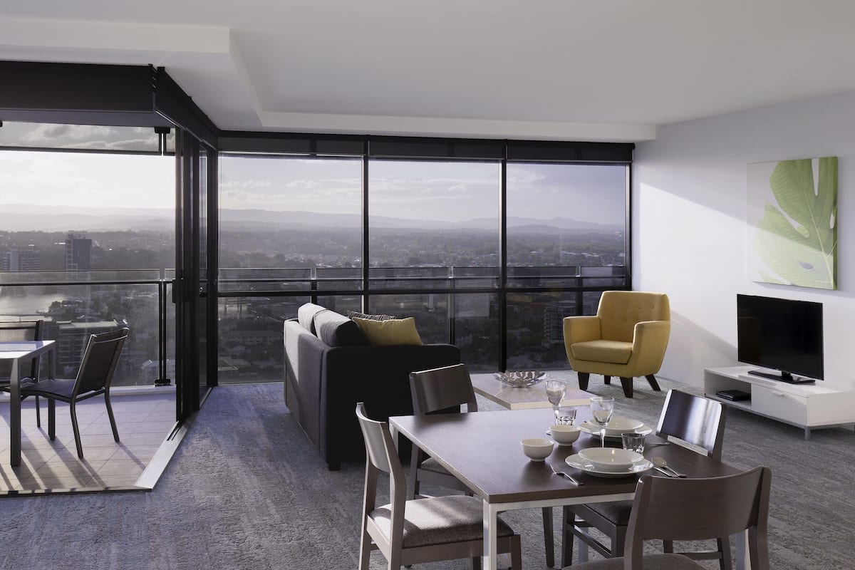 A modern living room with a city view, a dining area, and a flat-screen TV.