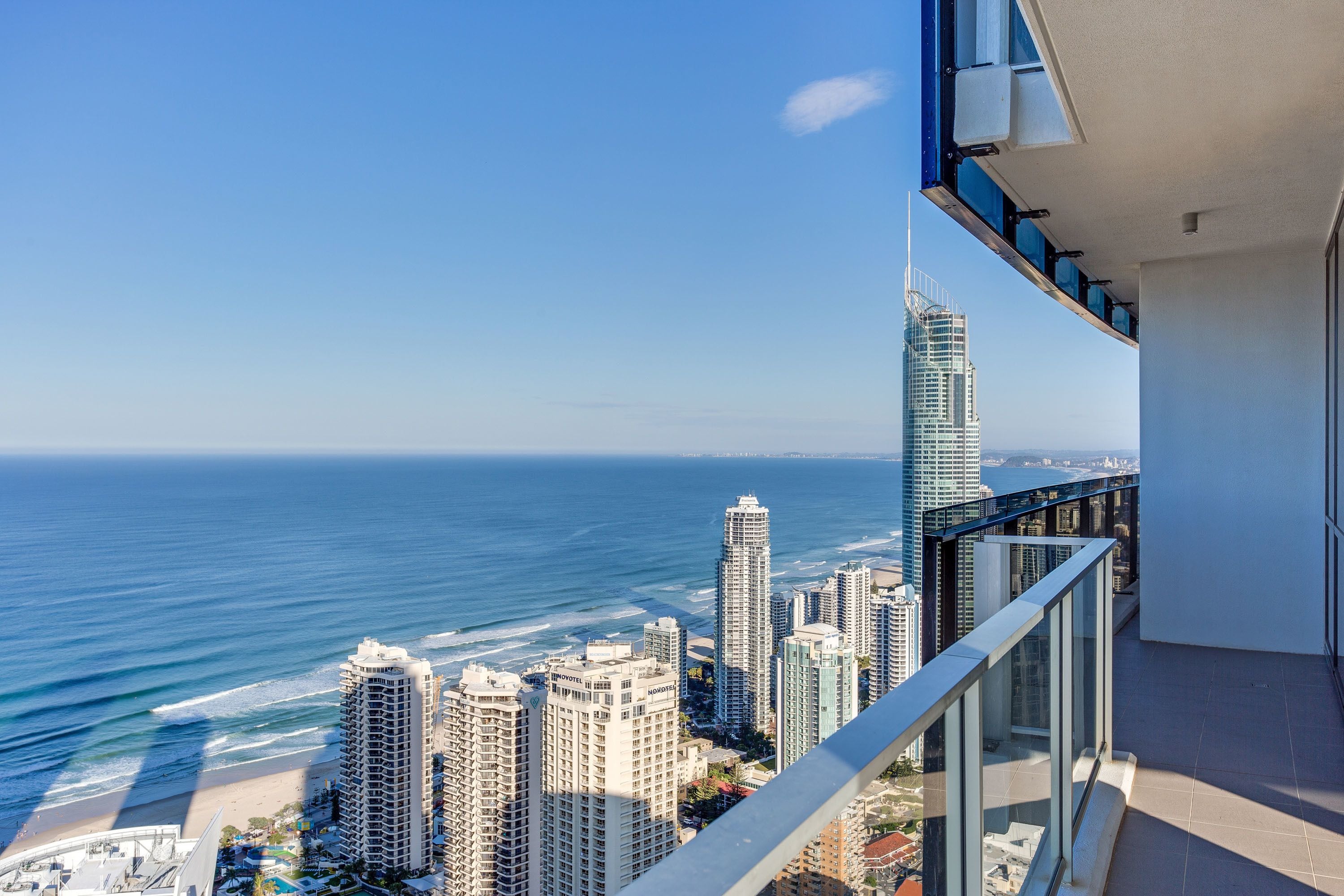 A high-rise building with a balcony overlooking a beach and ocean.
