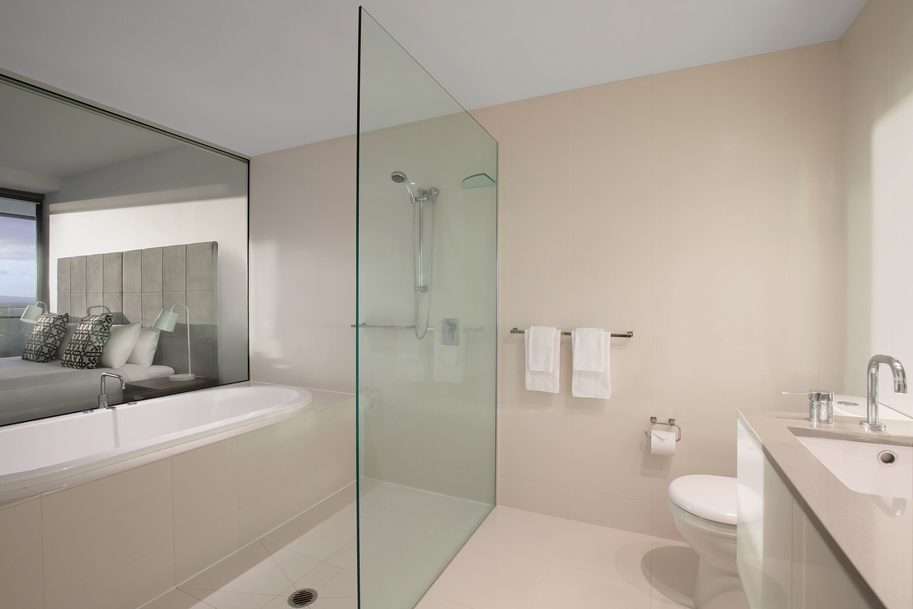 A modern bathroom with a glass-enclosed shower, a large bathtub, and a separate sink area.
