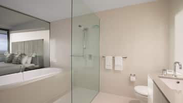 Un baño moderno con ducha de vidrio, una bañera amplia y un espacio separado para el lavamanos.