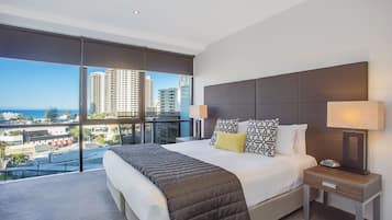 Een hotelkamer met een groot bed, twee nachtkastjes, uitzicht op de stad en een balkon.