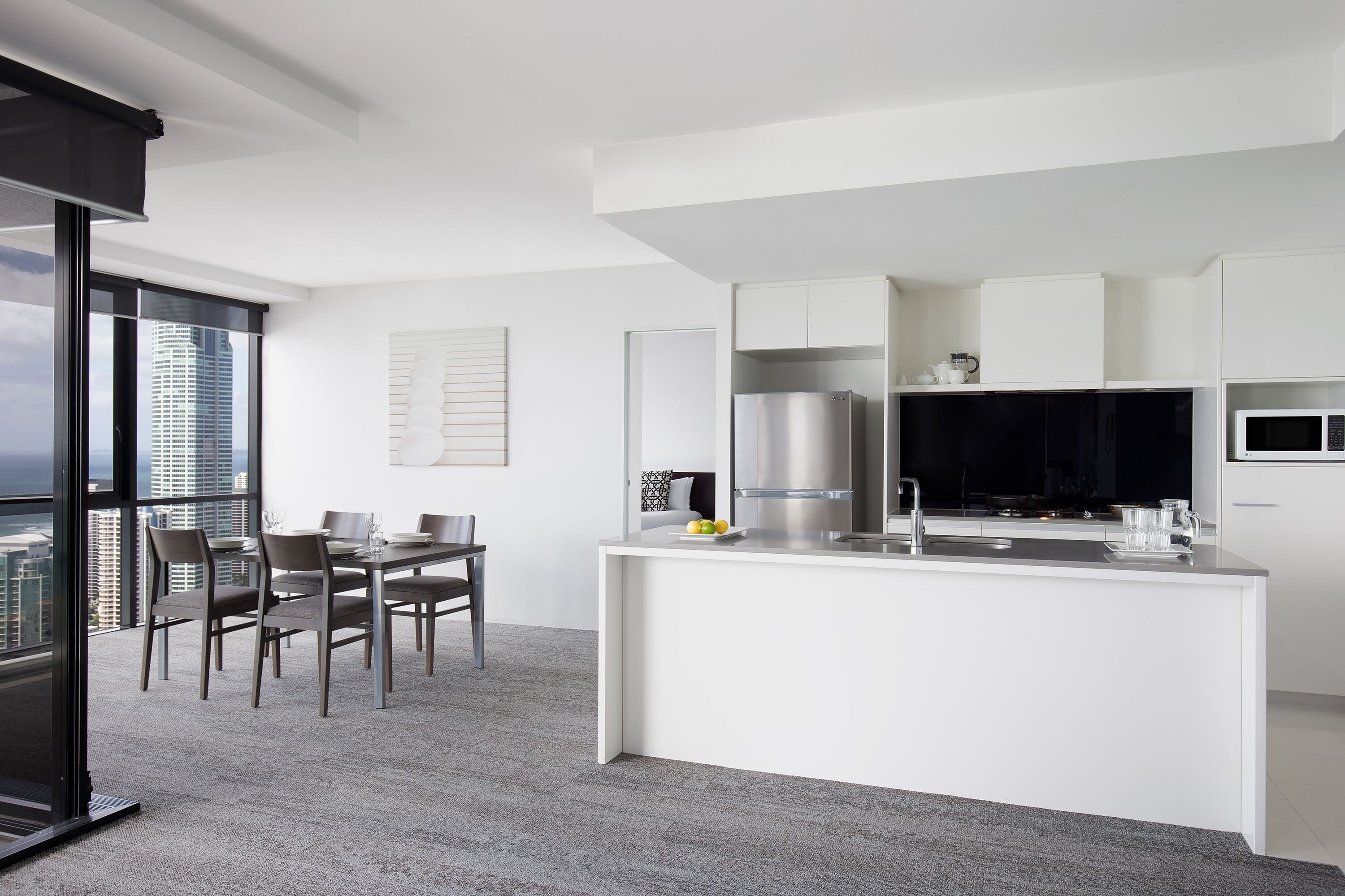 A modern kitchen with white cabinetry, a stainless steel refrigerator, and a black microwave.