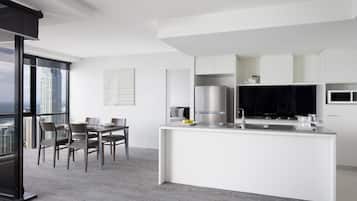 A modern kitchen with white cabinetry, a stainless steel refrigerator, and a black microwave.