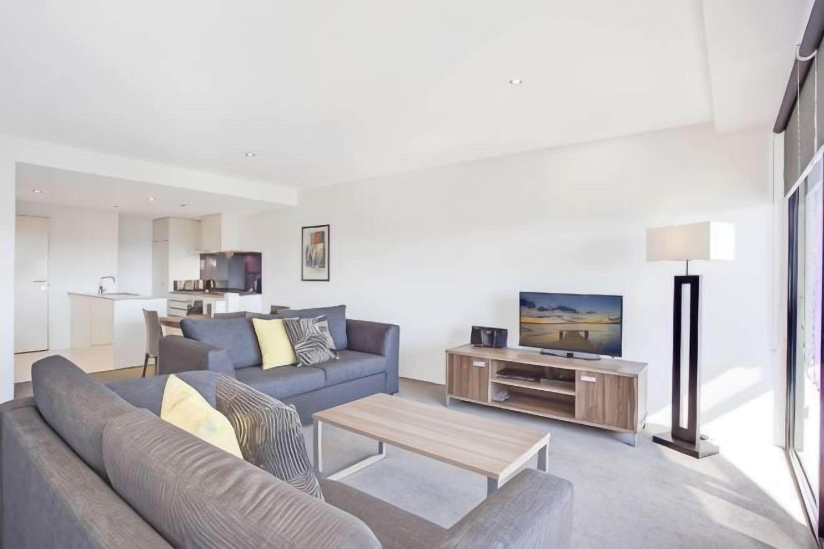 A modern living room with a sofa, coffee table, TV, and a lamp.
