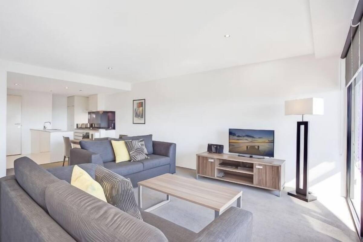 Ein modernes Wohnzimmer mit einer Couch, einem Couchtisch, einem Fernseher und einer Lampe.