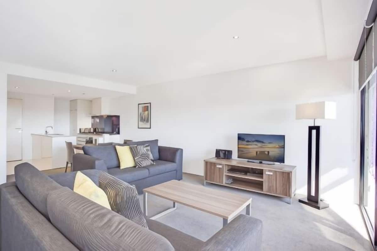 A modern living room with a sofa, coffee table, TV, and a lamp.