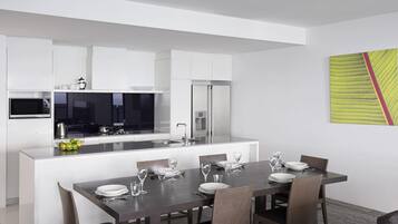 Una cocina moderna con gabinetes blancos, un microondas y un comedor con una mesa y sillas de madera oscura.