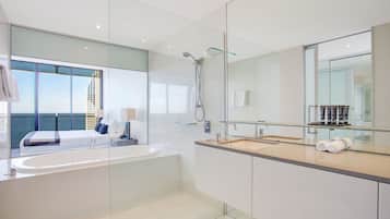 Un baño moderno con una bañera grande, una cabina de ducha de vidrio y un espejo amplio.