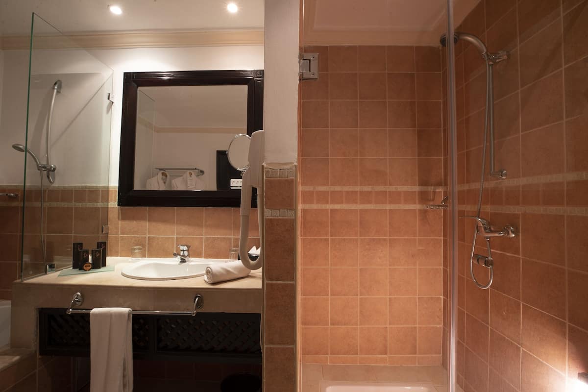 A bathroom with a glass-enclosed shower, a sink with a mirror above it, and a towel rack.
