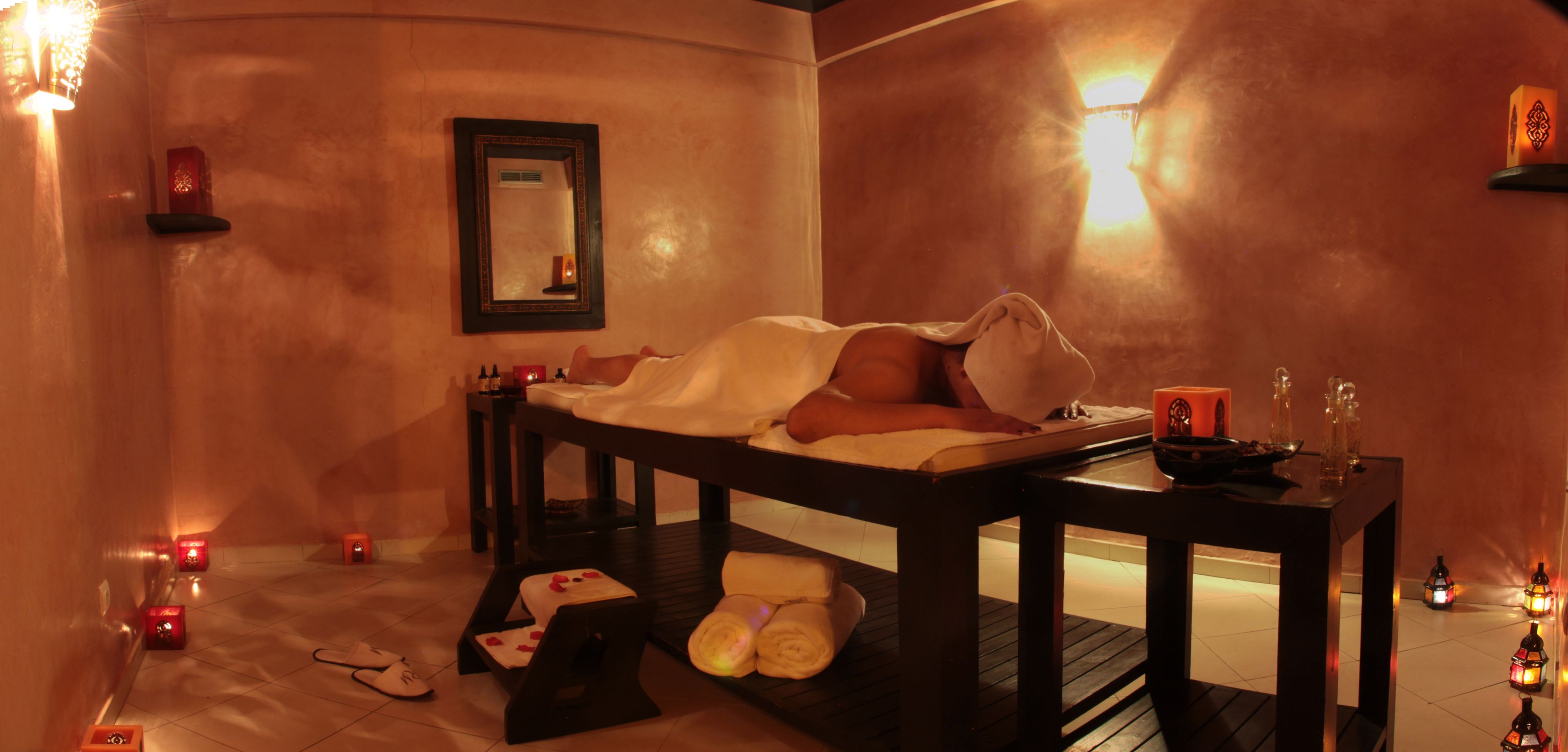 Un cuarto de spa con una camilla de masaje, velas y un espejo.