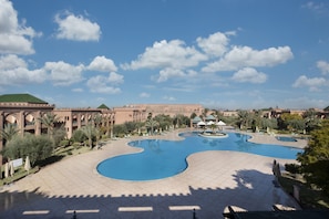 A resort with multiple swimming pools, palm trees, and a large building with arches. - Grand Mogador Agdal (Marrakech)