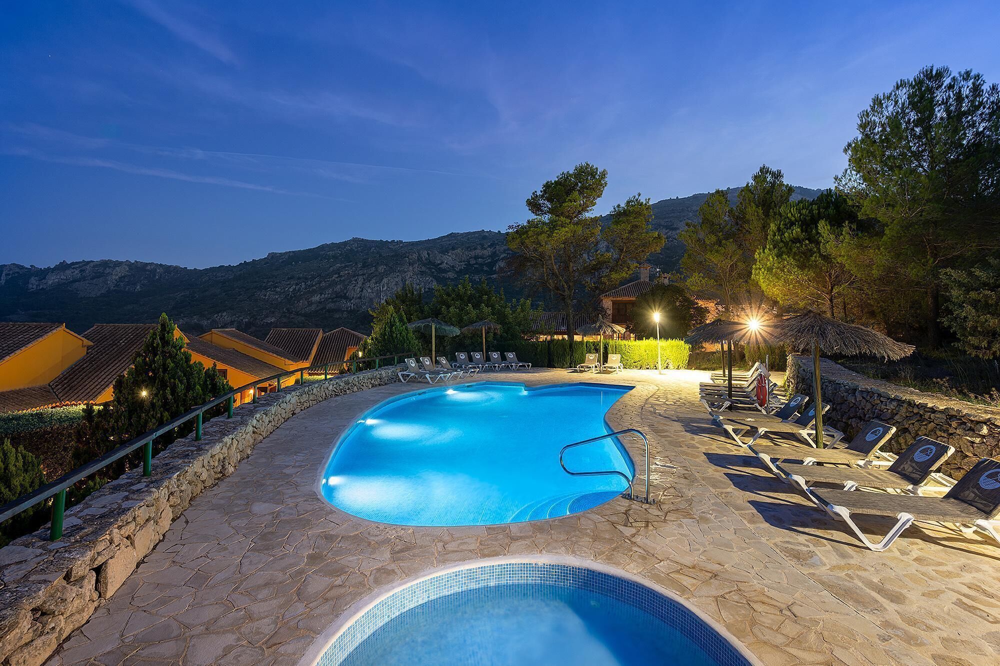 Una piscina al aire libre, sombrillas, sillones reclinables de piscina
