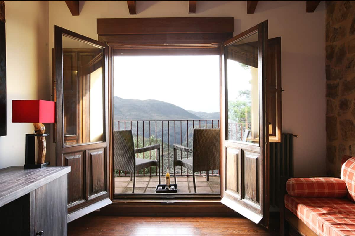 Une chambre avec balcon, des meubles en bois et une vue sur les montagnes.