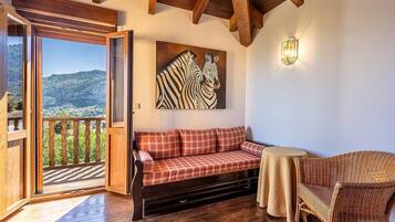 Una habitación acogedora con un banco de madera, una silla de mimbre y un amplio ventanal con vistas a un paisaje montañoso.