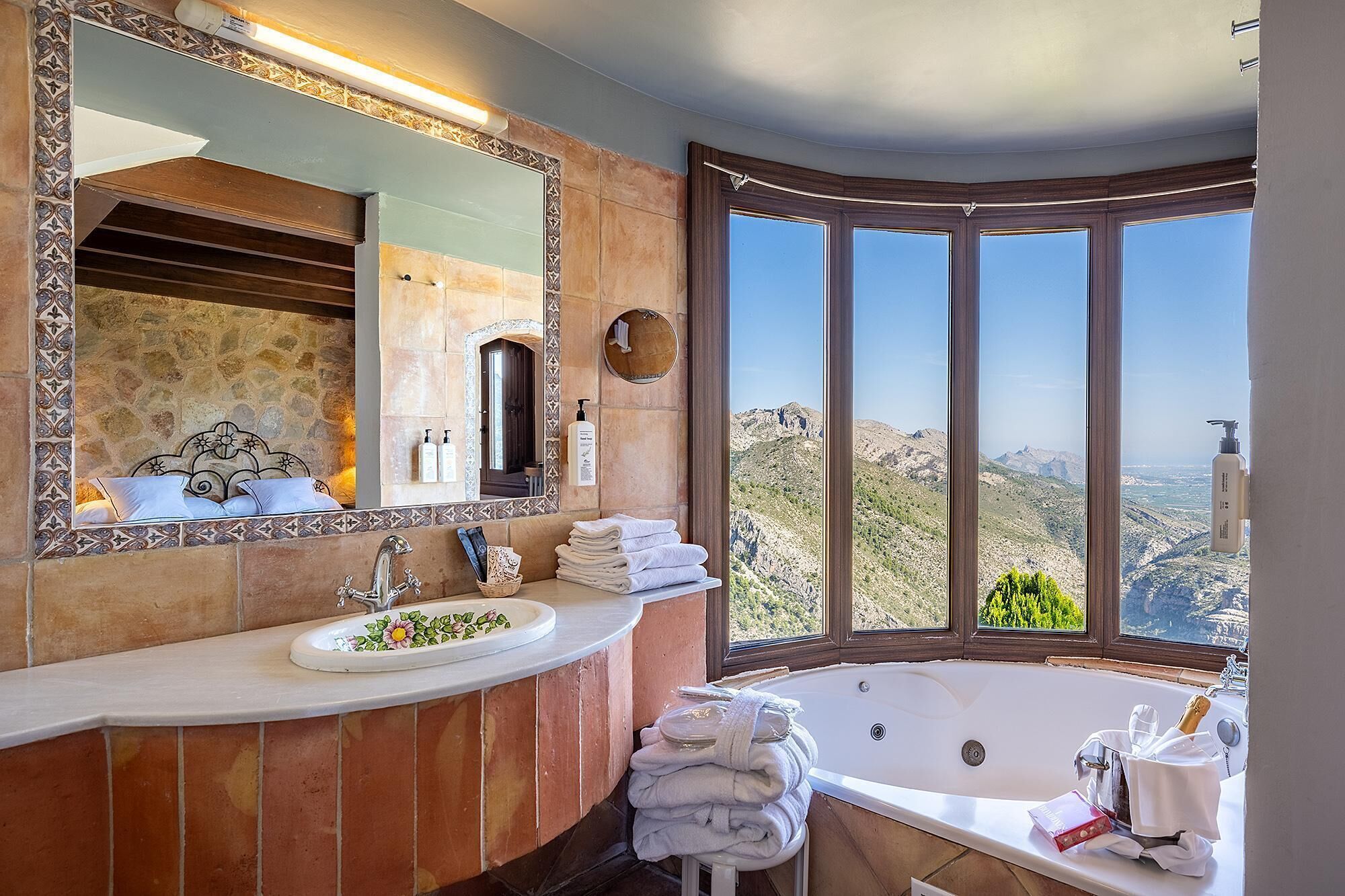 A bathroom with a large window, a bathtub, a sink, and a mirror.