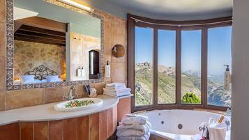 A bathroom with a large window, a bathtub, a sink, and a mirror.