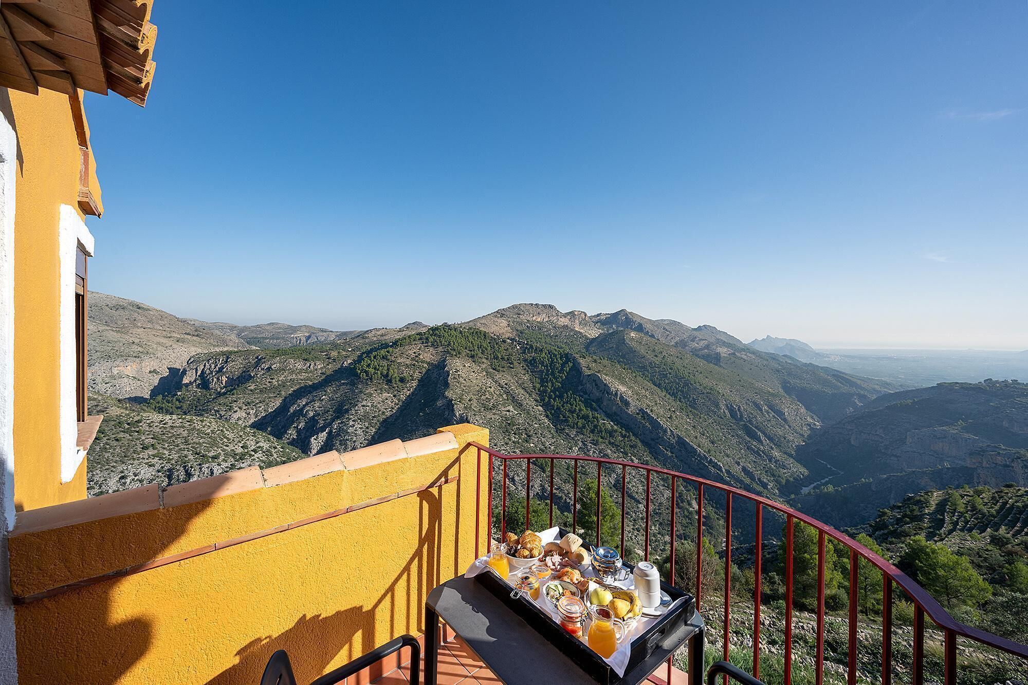Balcón con una bandeja de desayuno con vistas a un paisaje montañoso.