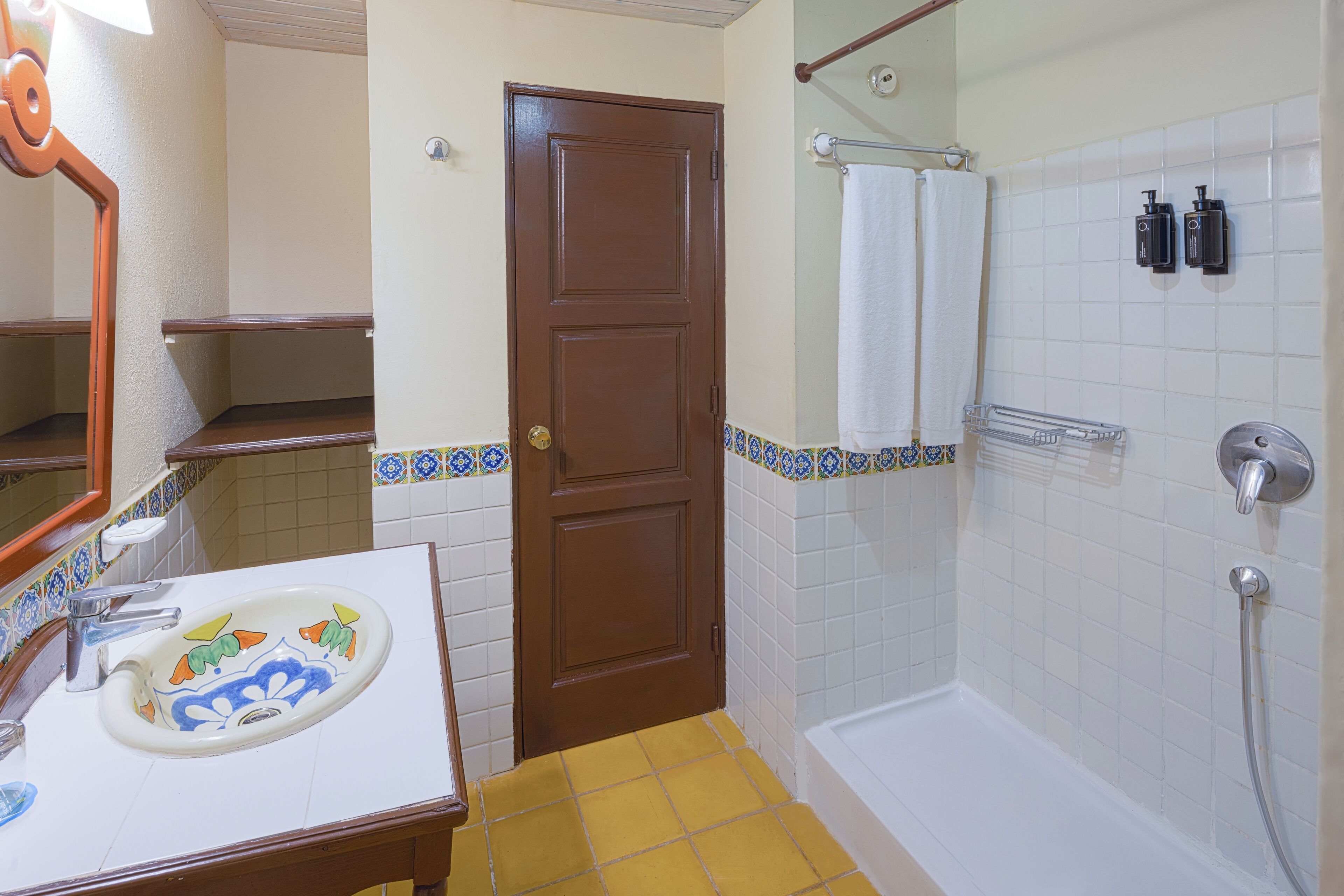 Une salle de bain équipée d’un lavabo, d’un miroir, d’une porte et d’un espace douche.