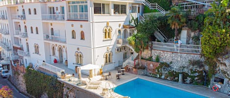 Un hotel con piscina, varios balcones y una escalera que conduce a los pisos superiores.