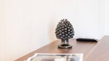 A wooden table with a decorative pine cone ornament and a remote control.