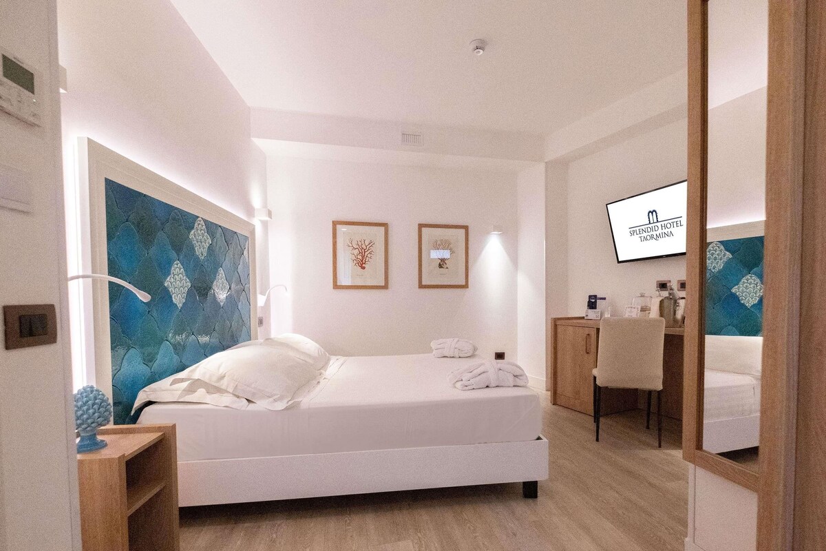 A modern hotel room with a bed, bedside table, and a mirror.