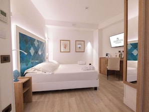 Habitación de hotel moderna con cama, mesita de noche y espejo.